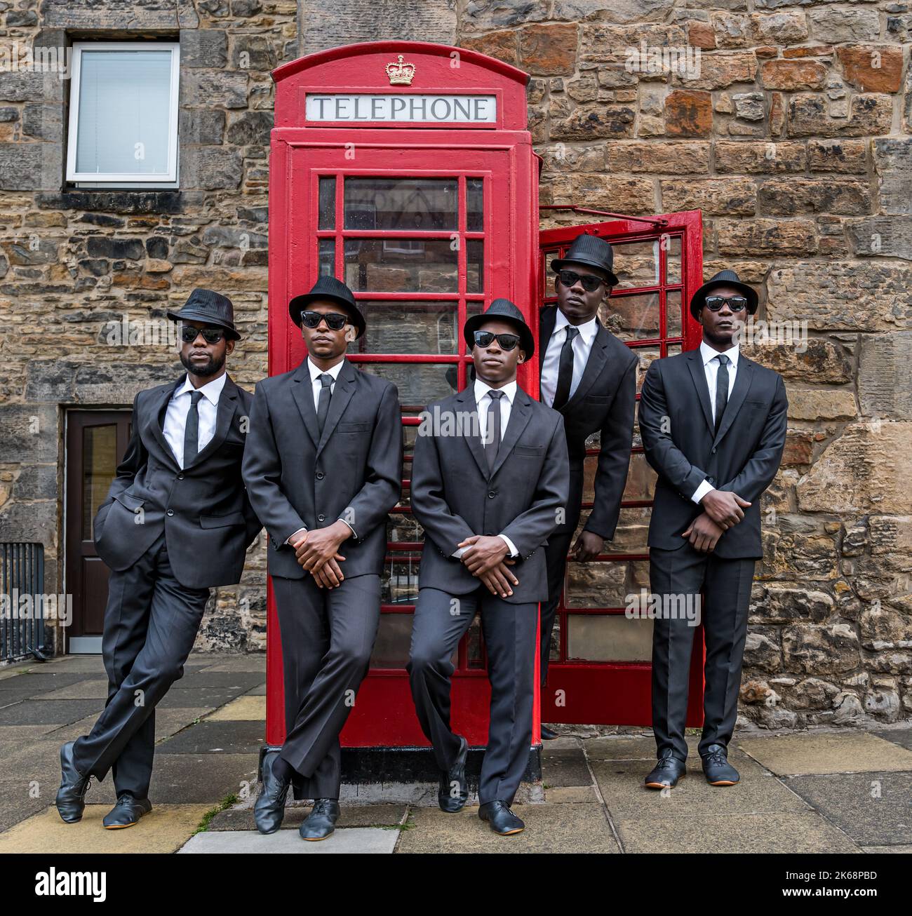 Black Blues Brothers acrobatic group perform in Dean Village by a red telephone box, Edinburgh, Scotland, UK Stock Photo