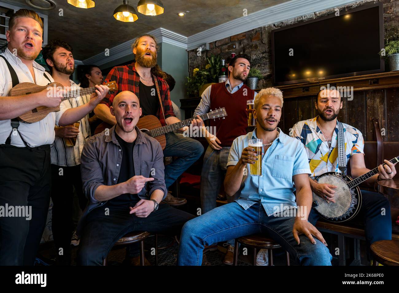 Choir of Man group singing, playing music and drinking beer in a pub, Grassmarket, Edinburgh, Scotland, UK Stock Photo