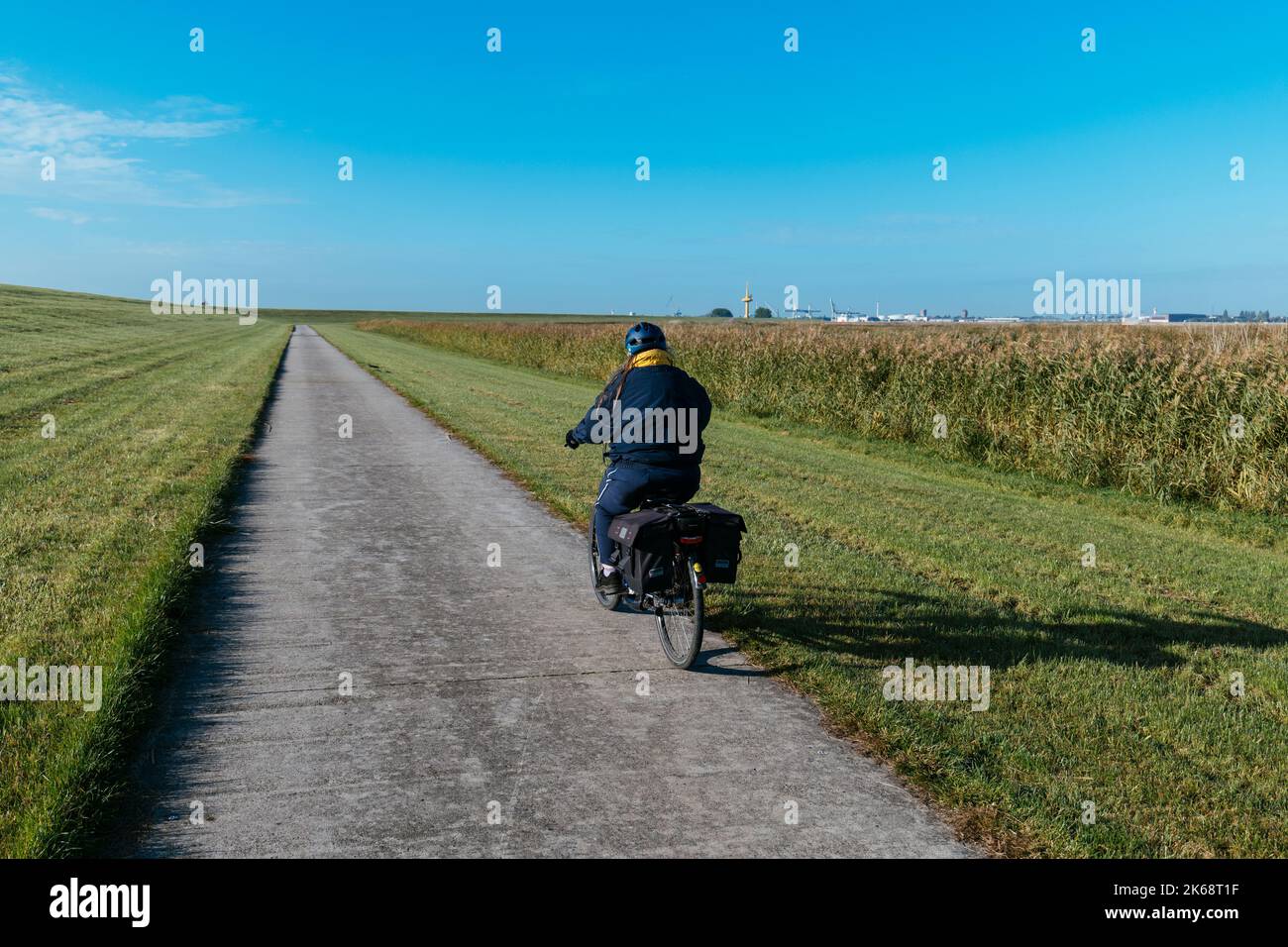 Woman on a bicycle going south on the Weser cycle path south of Bremerhaven. Stock Photo
