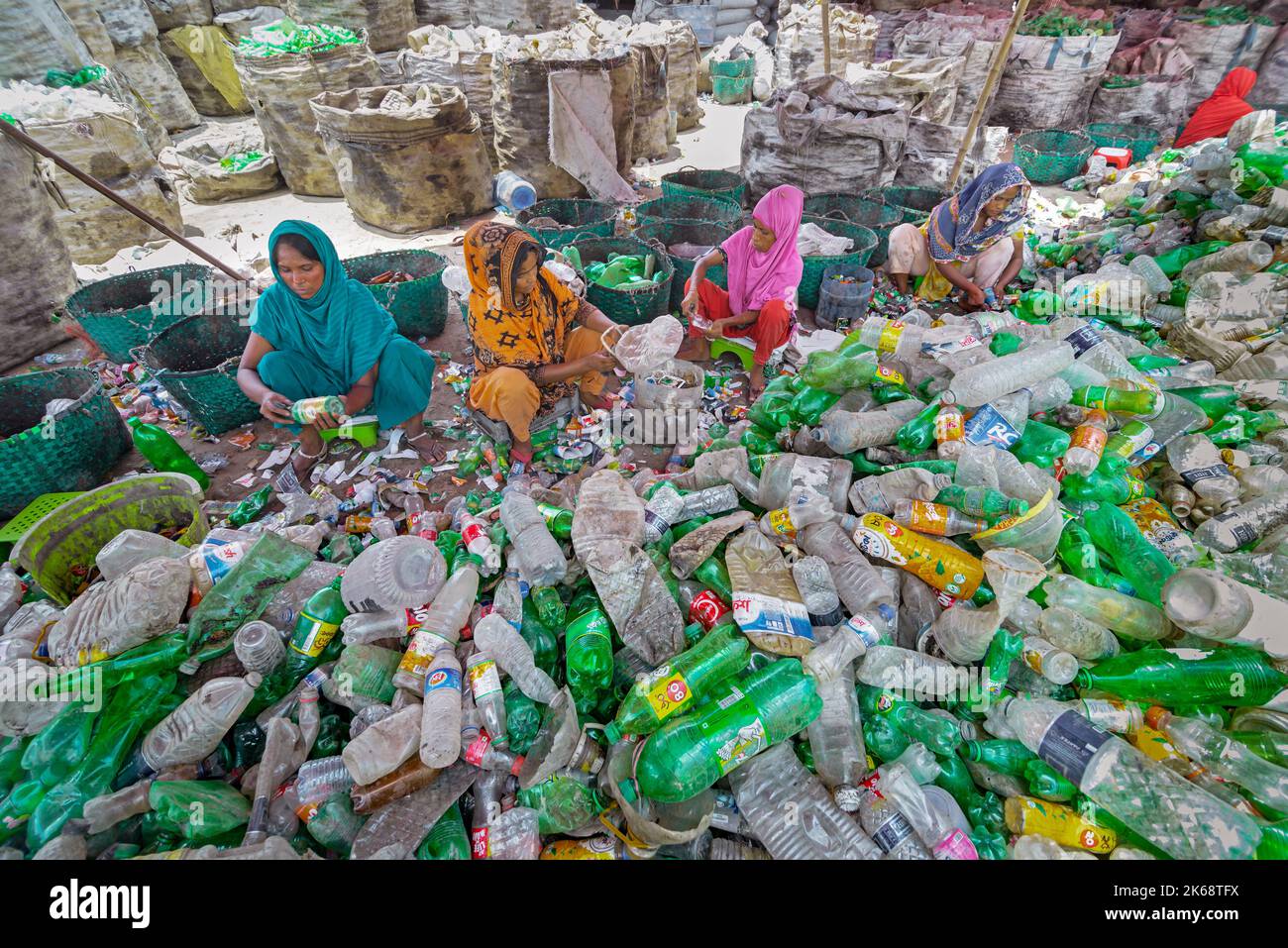 Workers sort used plastic bottles at a recycling factory. Recycle of plastics is the best way to make our environment clean and safe. Stock Photo