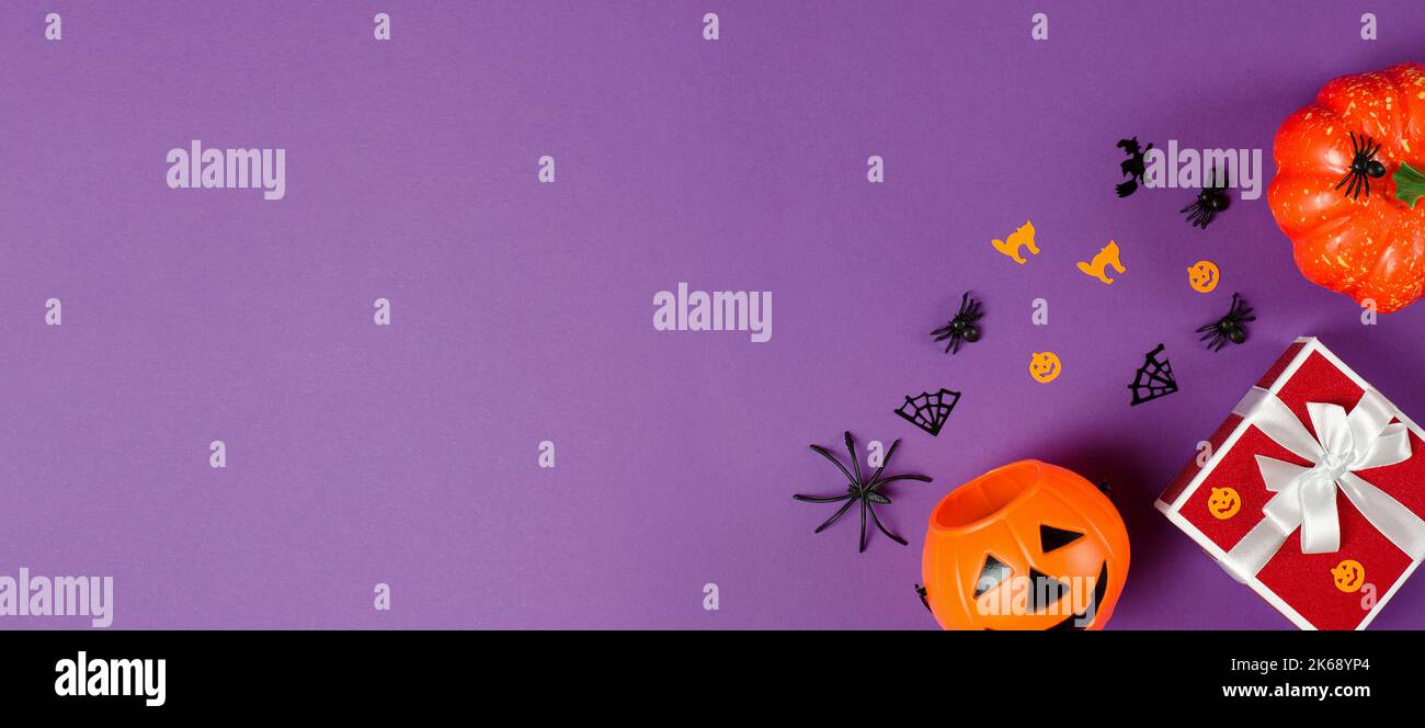 Red gift box and traditional halloween decorations on purple background,copy space. Halloween Gifts and Sale Stock Photo
