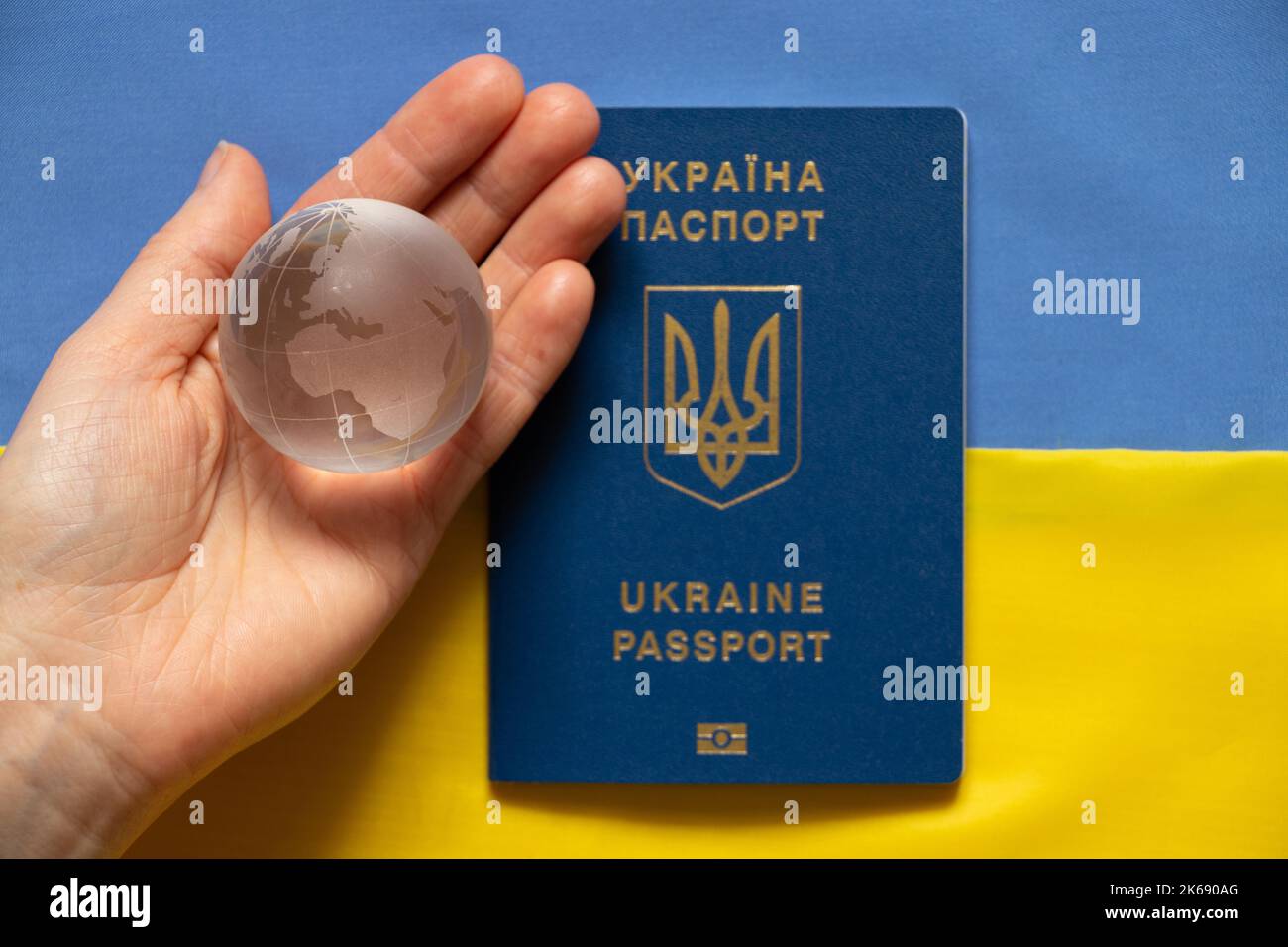 The flag of Ukraine is yellow and blue, and the hand holds a globe and a foreign passport. Martial law in Ukraine 2022. Stop the war. Peace and Journe Stock Photo
