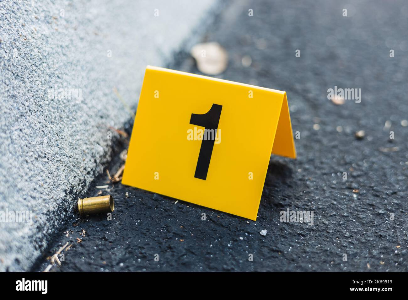 One yellow crime scene evidence marker on the street after a gun