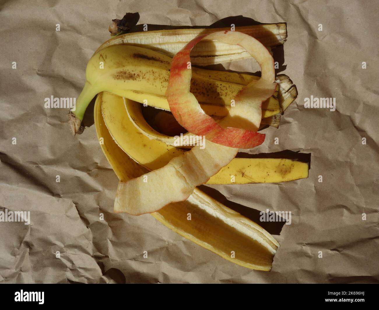 Banana and apple peels, biodegradable waste on crumpled wrapping paper