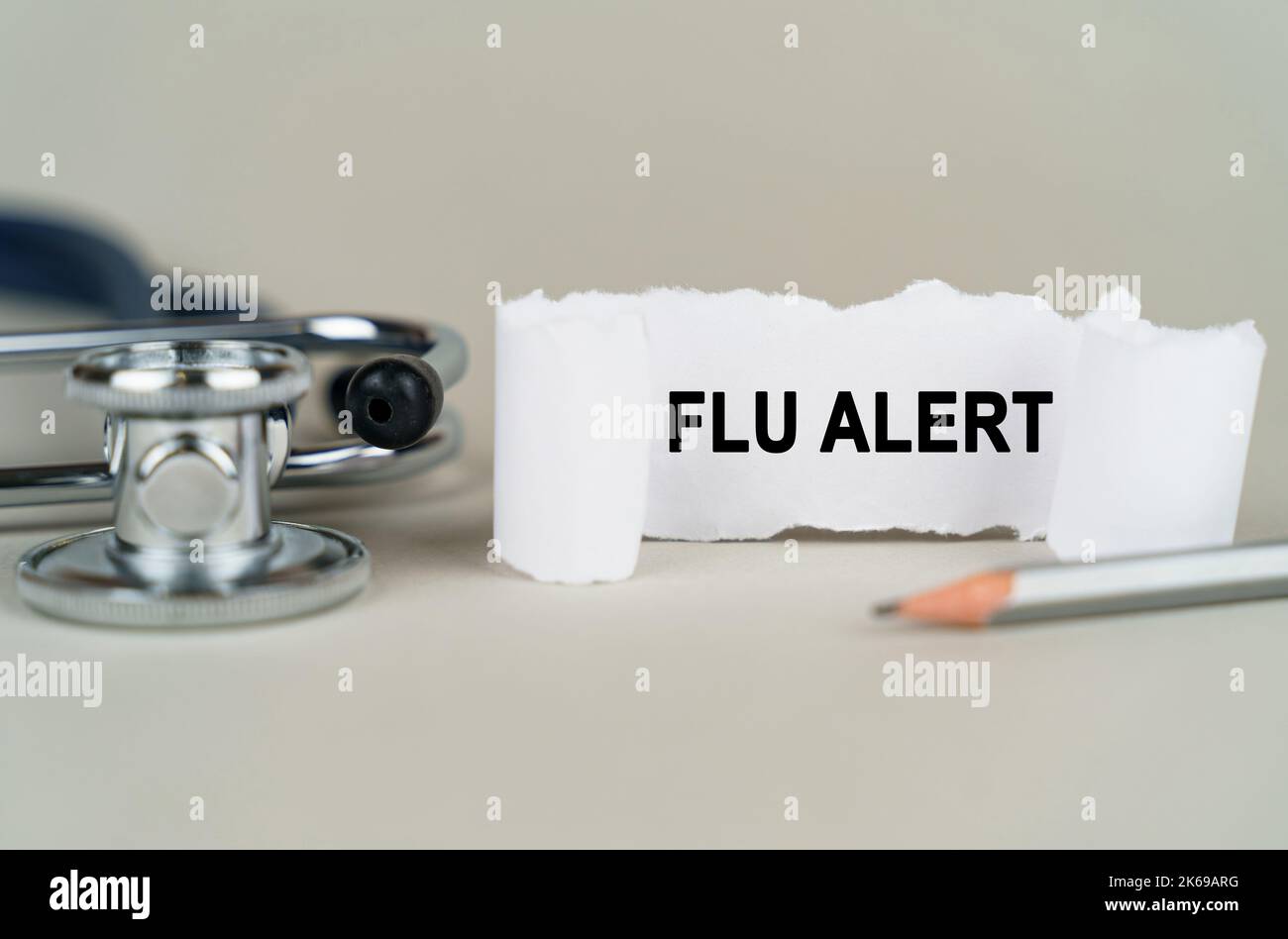 Medical concept. On a gray background, a stethoscope, a pencil and a paper plate with the inscription - Flu alert Stock Photo