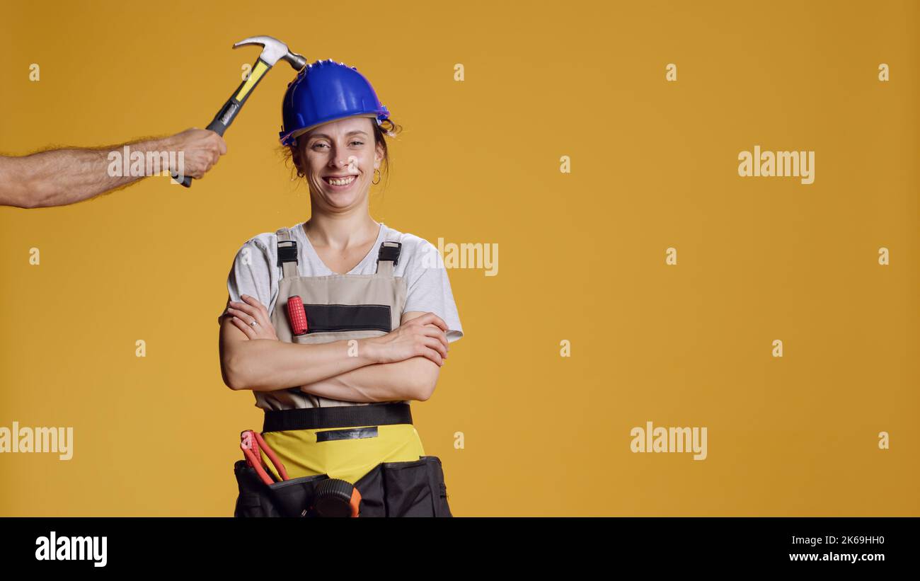 Portrait of female builder being hit in head and feeling dizzy, seeing stars in eyes and acting disorientated or light headed. Unsteady shaky woman feeling weak and wobbly, looney tunes. Stock Photo