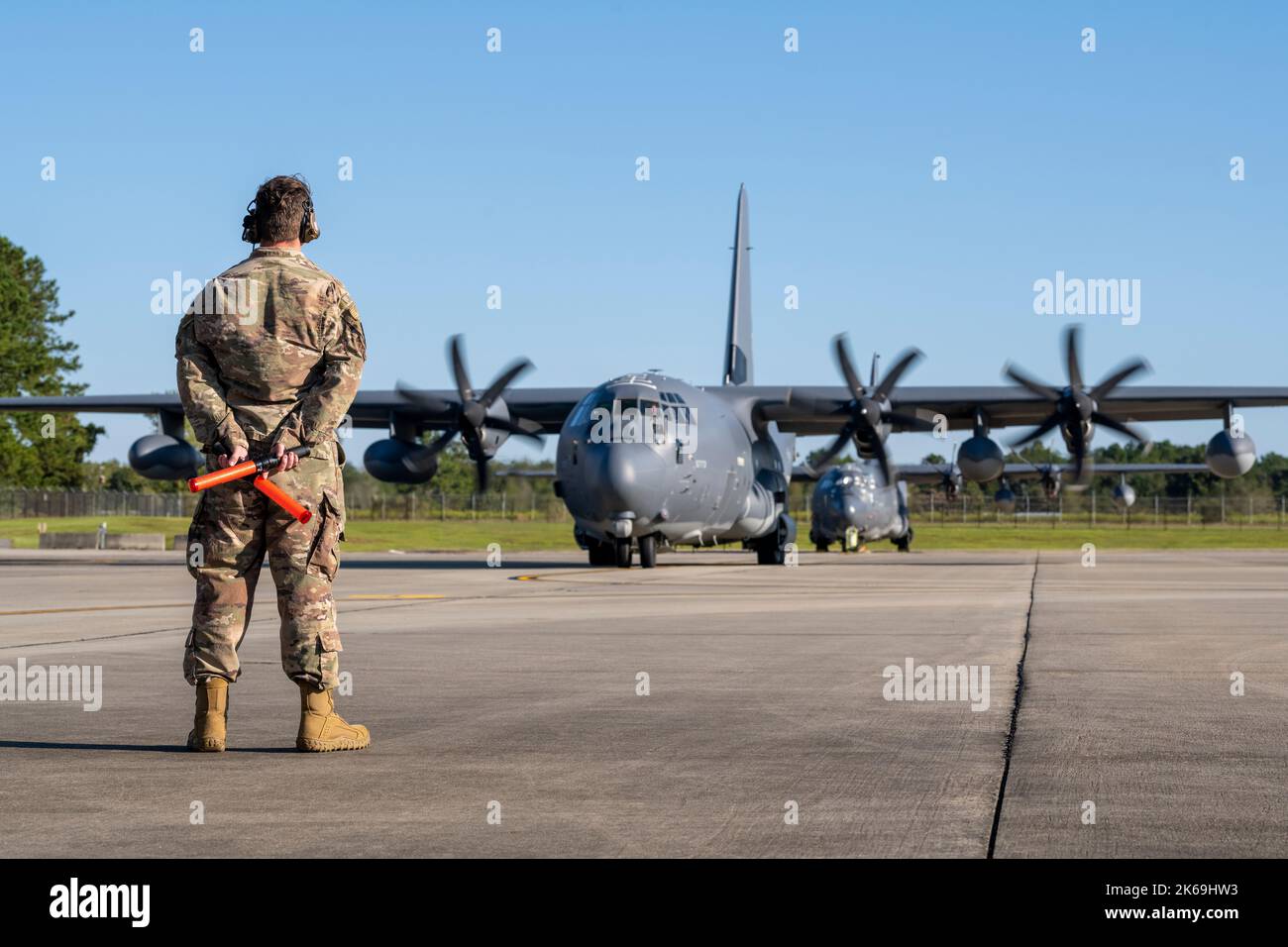 A U.S. Air Force Airman prepares to marshal an HC-130J Combat King II at Moody Air Force Base, Georgia, Sept. 23, 2022. Aircraft marshaling is visual communication between ground personnel and pilots that guides them to turn, slow down, stop, and lead them to a parking spot or the runway. Moody Airmen set out on the first-ever operational deployment of the HH-60W to provide rescue services in support of contingency operations. (U.S. Air Force photo by Airman 1st Class Deanna Muir) Stock Photo