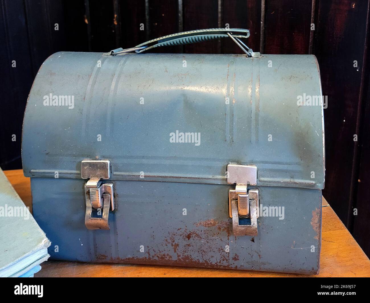 Old dented blue metal lunch pail with a book on a wooden table Stock Photo Alamy