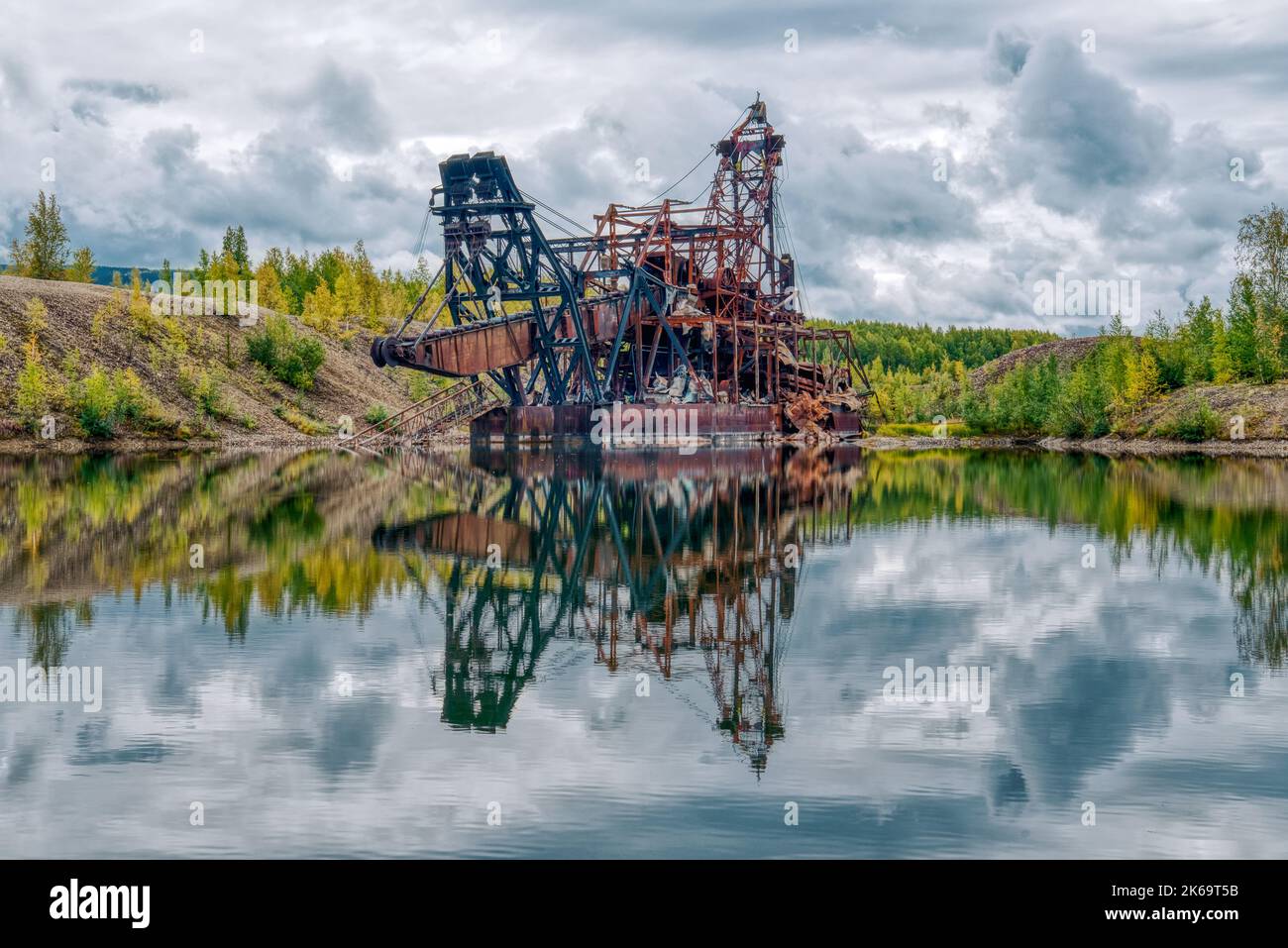 Old rusty abandoned gold mining dredge in a pond in Alaska Stock Photo