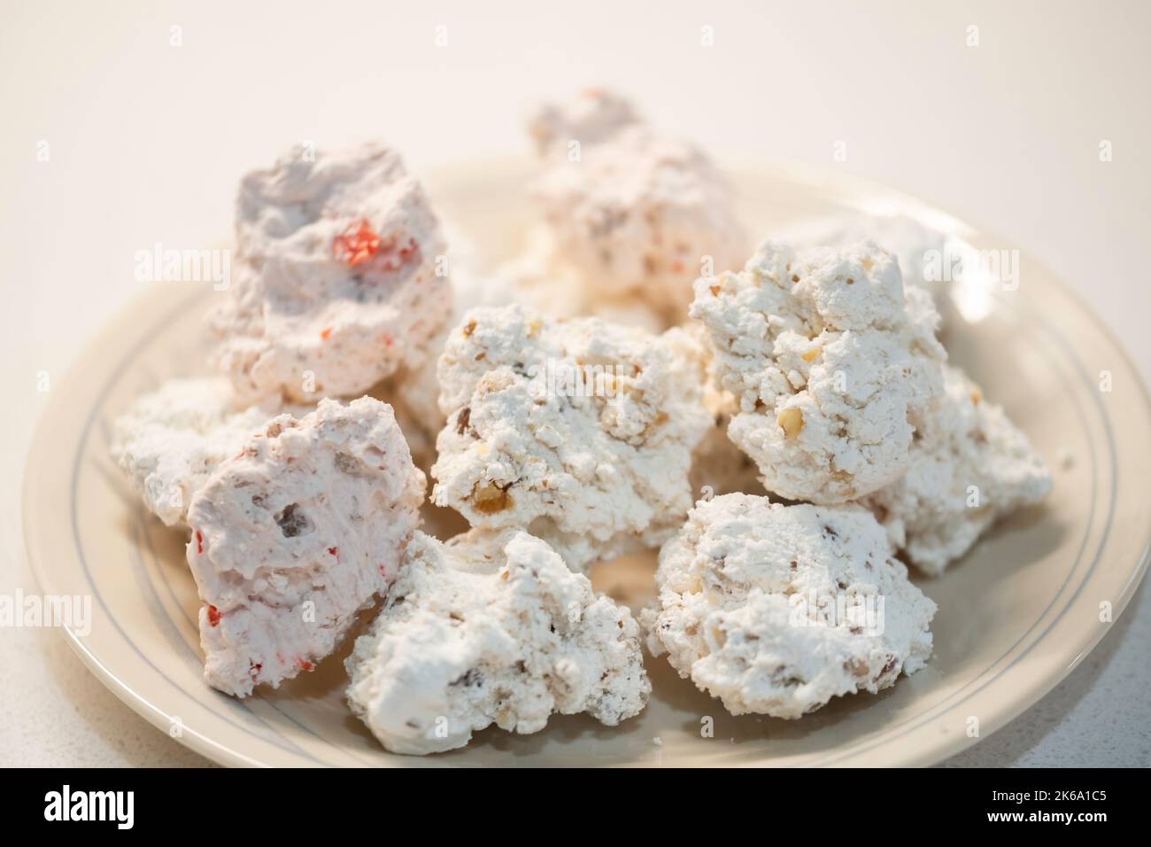 Homemade divinity candy, a mix of pecan and cherry pecan divinity in a plate sat on a white tcountertop. USA. Stock Photo