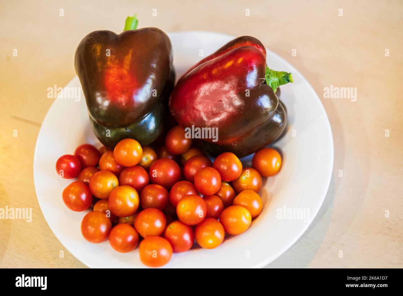 Cherry tomatoes or grape tomatoes. Home grown. Indeterminate, hybrid cultivar. Super Sweet 100 variety, with red bell peppers, Capsicum annuum. Stock Photo