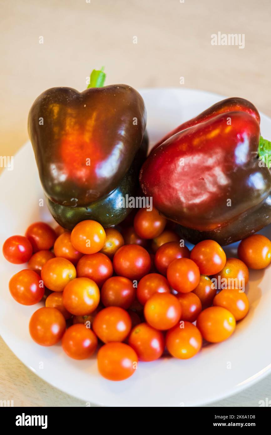 Cherry tomatoes or grape tomatoes. Home grown. Indeterminate, hybrid cultivar. Super Sweet 100 variety, with red bell peppers, Capsicum annuum. Stock Photo