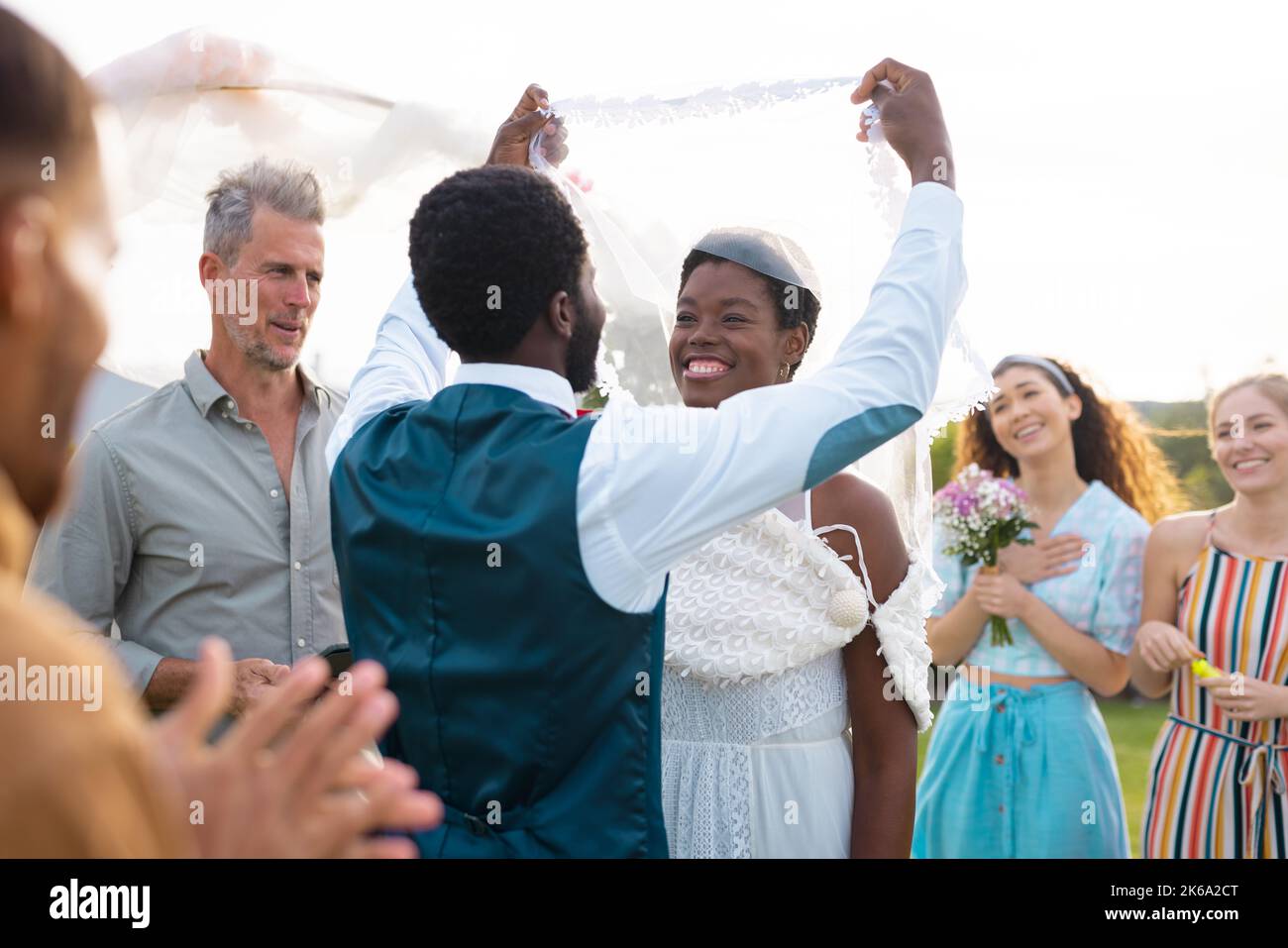 Happy african american couple holding veil and smiling during wedding ...