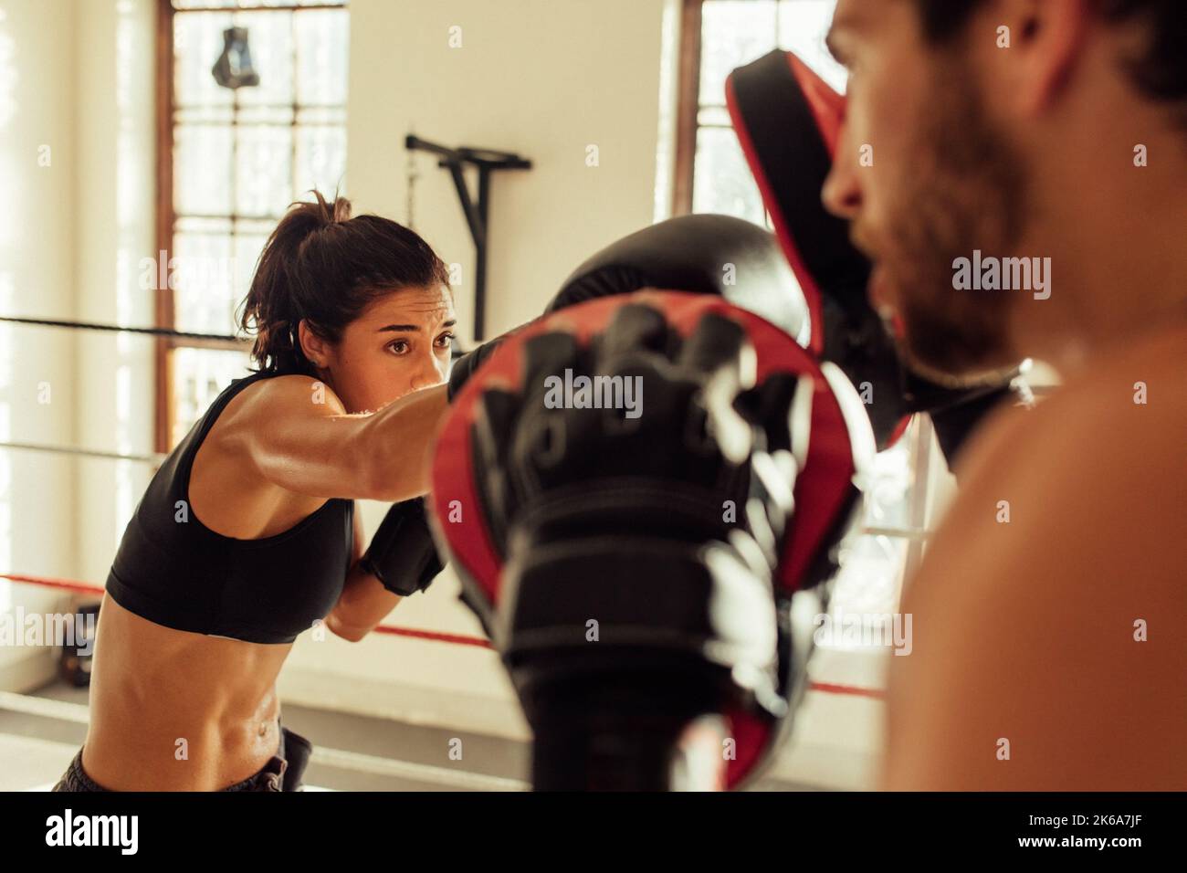 Beautiful young female pugilist throws a punch at male partner with beard Stock Photo