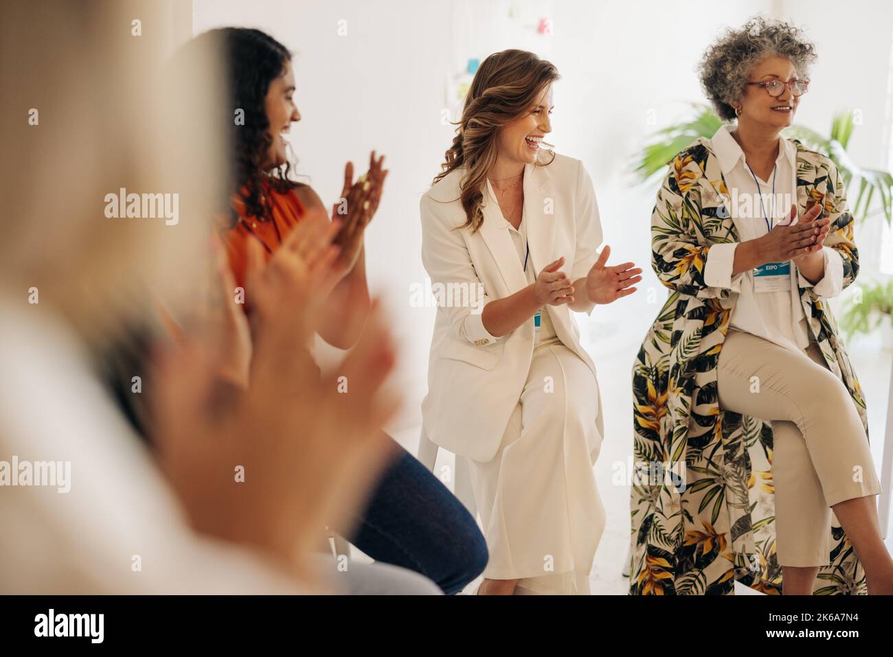 Smiling businesswomen applauding during a conference meeting. Group of multicultural businesswomen celebrating their achievement. Successful businessw Stock Photo