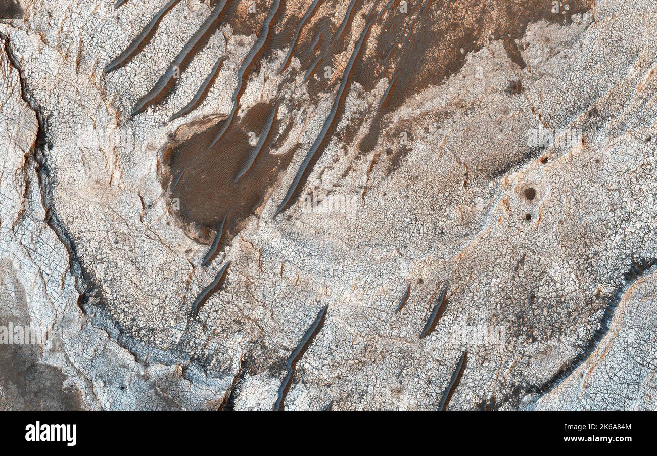 Erosion of Mars surface reveals several shades of light toned layers, likely sedimentary deposits. Stock Photo