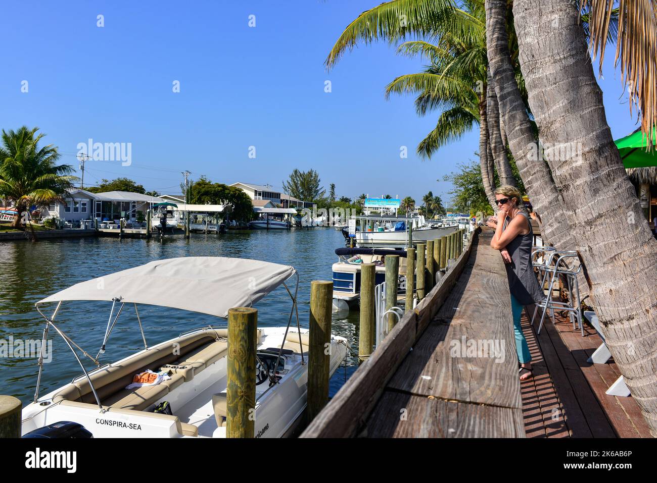 Woman viewing Boats docks along Crowded canal  near Phuzzys Boat Shack restaurant & bar in St. James City, Pine Island on Charlotte Harbor, Florida, b Stock Photo