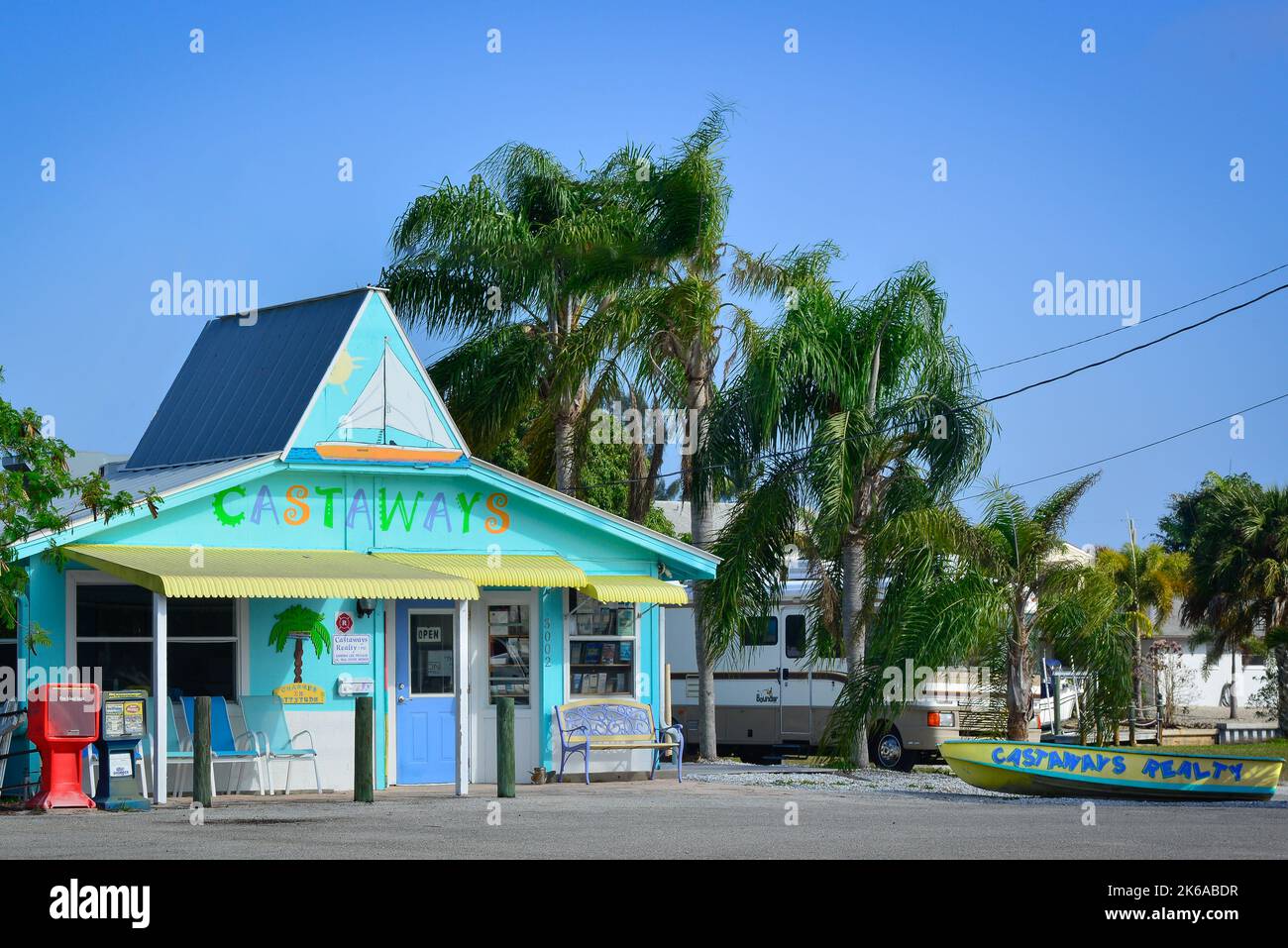 A charming little building in colorful pastels houses the Castaways Realty business with boat parked out front in St. James City, Pine Island, FL, USA Stock Photo