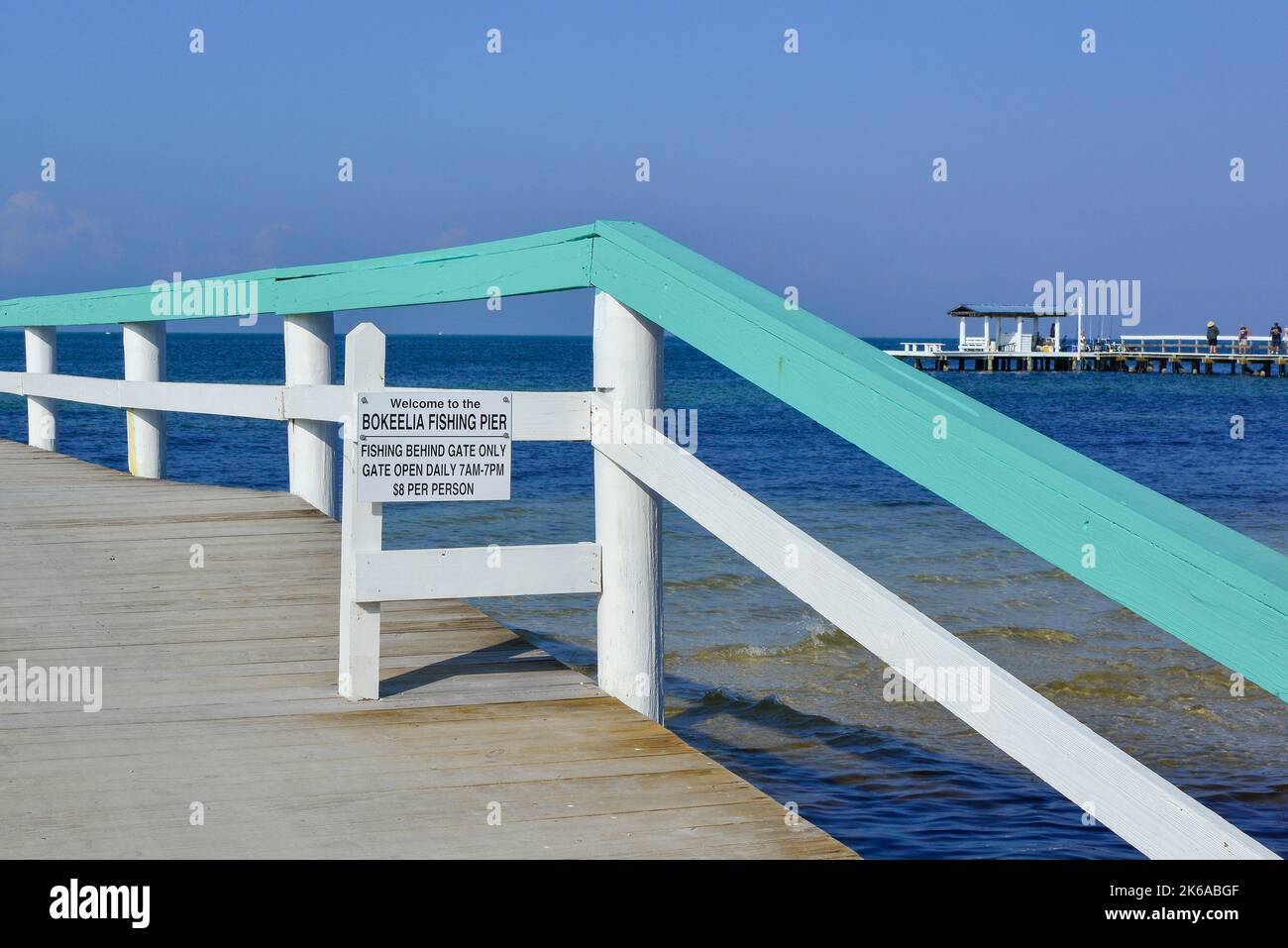 The waterfront of Charlotte Harbor from the Bokeelia Fishing Pier, with sign noting fees beyond gate at the pier for fisherman only on Pine Island, FL Stock Photo