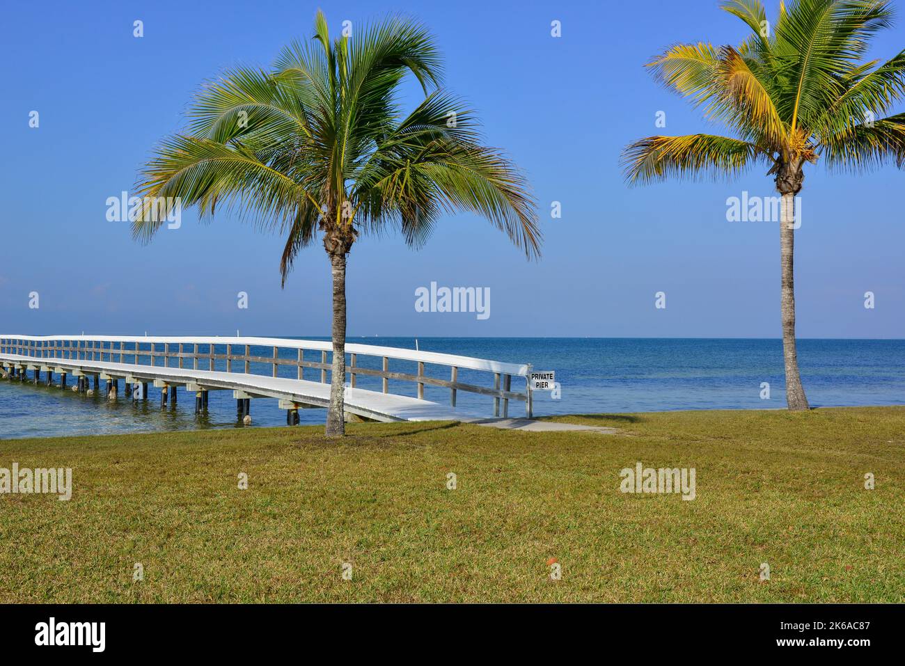 A serene panoramic view over the Charlotte Harbor of a wooden pier and palm trees in  Bokeelia, Florida, on Pine Island, quintessential Old Florida Stock Photo