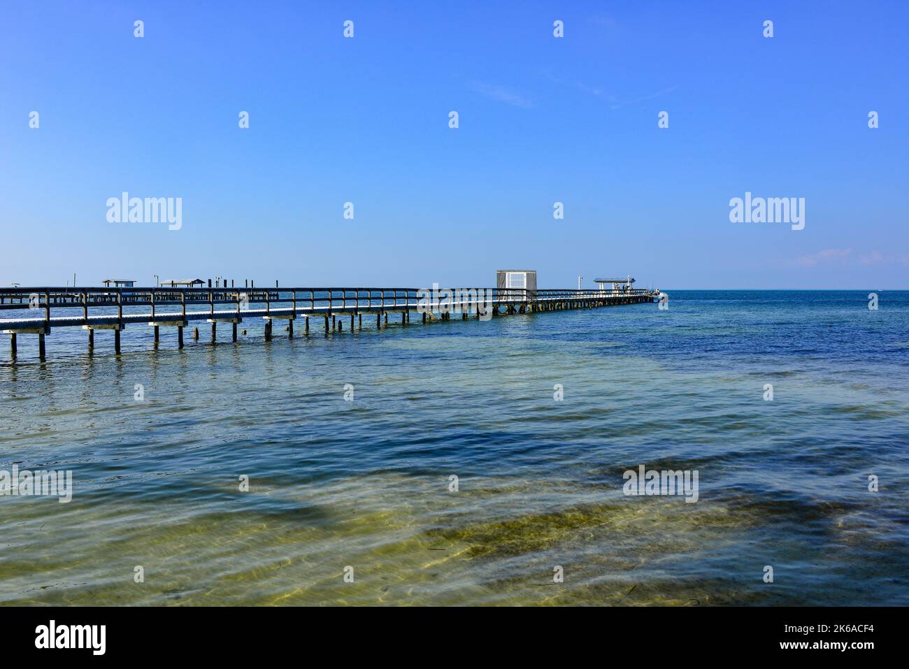 Brackish water in Charlotte Harbor with fishing piers and docks extending into the minimal landscape of water with blue sky, Bokeelia, Pine Island, FL Stock Photo