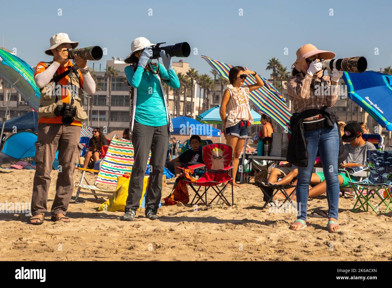 Male and female Asian American amateur photographers focus on a July Fourth air show in Huntington Beach, CA. Stock Photo
