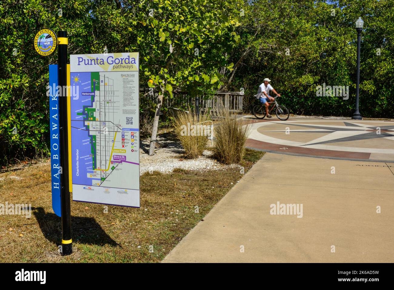 Harborwalk sign for City of Punta Gorda with map with Bicyclist enjoying the  paths in Trabue Park on the Harborwalk in Punta Gorda, Florida Stock Photo