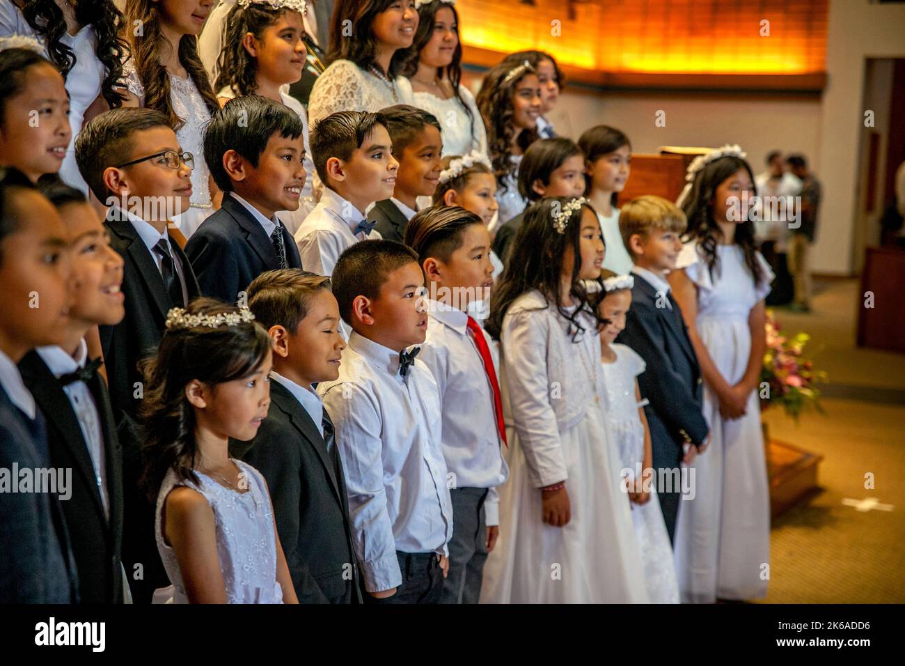 Formally dressed multiracial children pose after their first communion