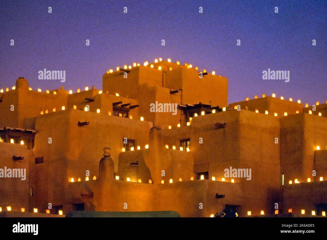 Luminara lights decorate a Pueblo style building in Santa Fe, New Mexico, at Christmas. A luminaria or farolito is a small candle set in sand inside a Stock Photo
