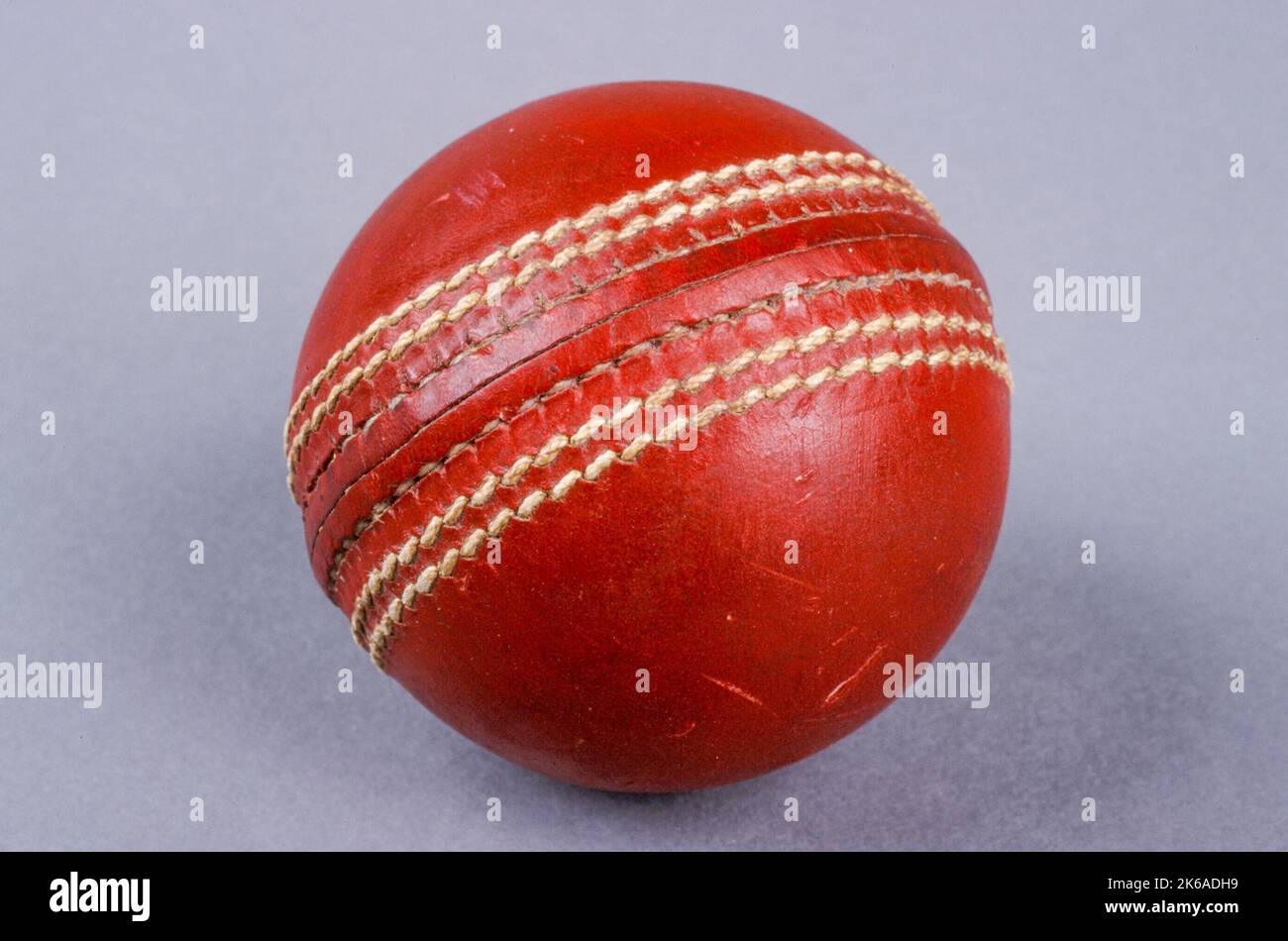 A red leather traditional cricket ball. Cricket is the world's most