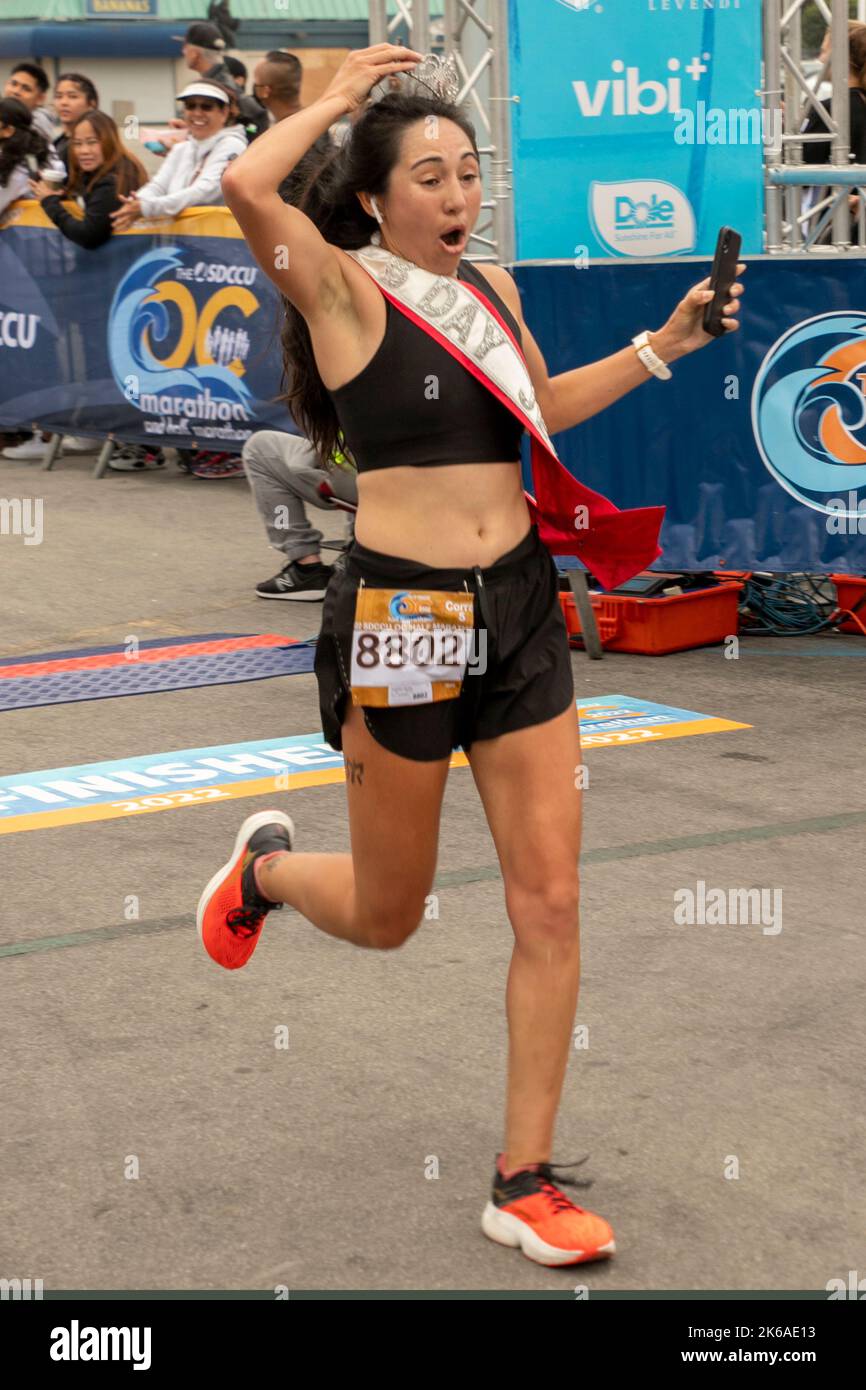 Wearing a "Happy Birthday Jen" sash, a half marathon runner crosses the