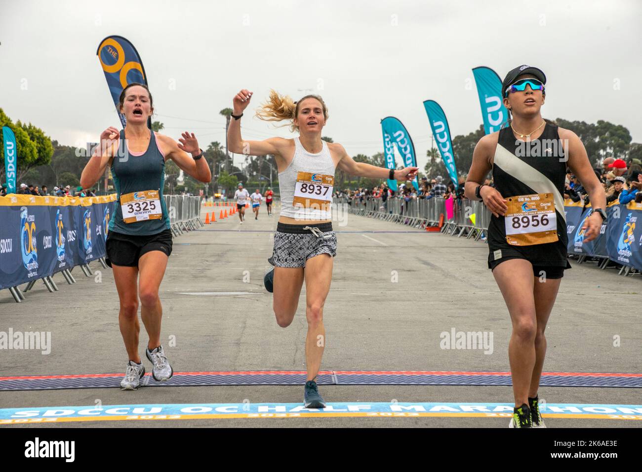 Three female competitors cross the finish line of a half marathon in