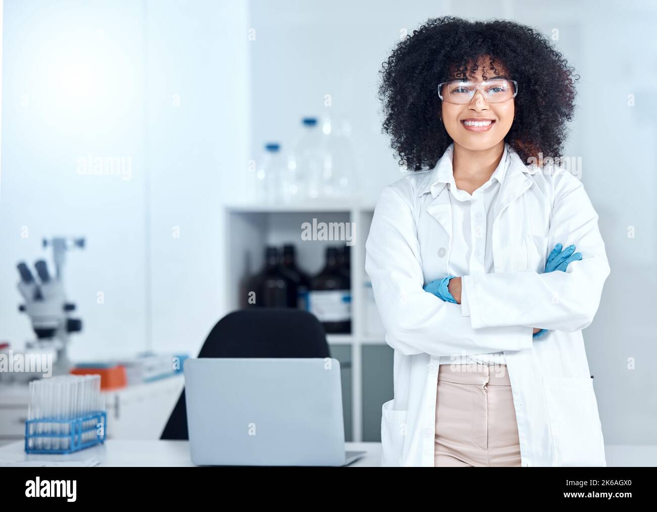 Portrait of proud african american scientist wearing safety goggles in her office. Smiling medical professional with her arms crossed wearing a lab Stock Photo