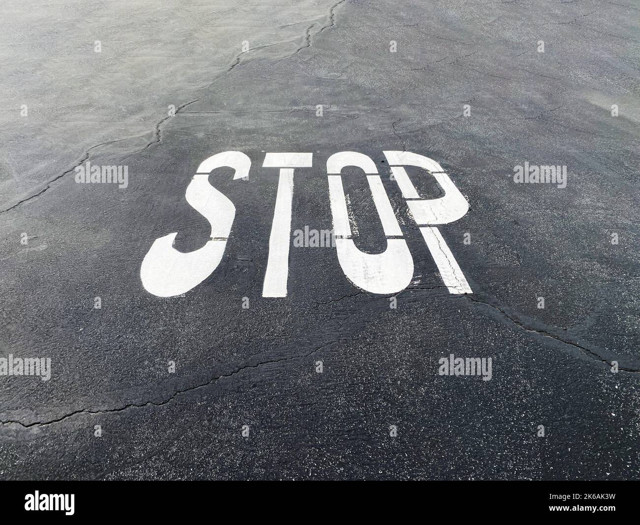 a paved road asphalt stop sign painted roadway intersection warning symbol street signage industrial backdrop Stock Photo
