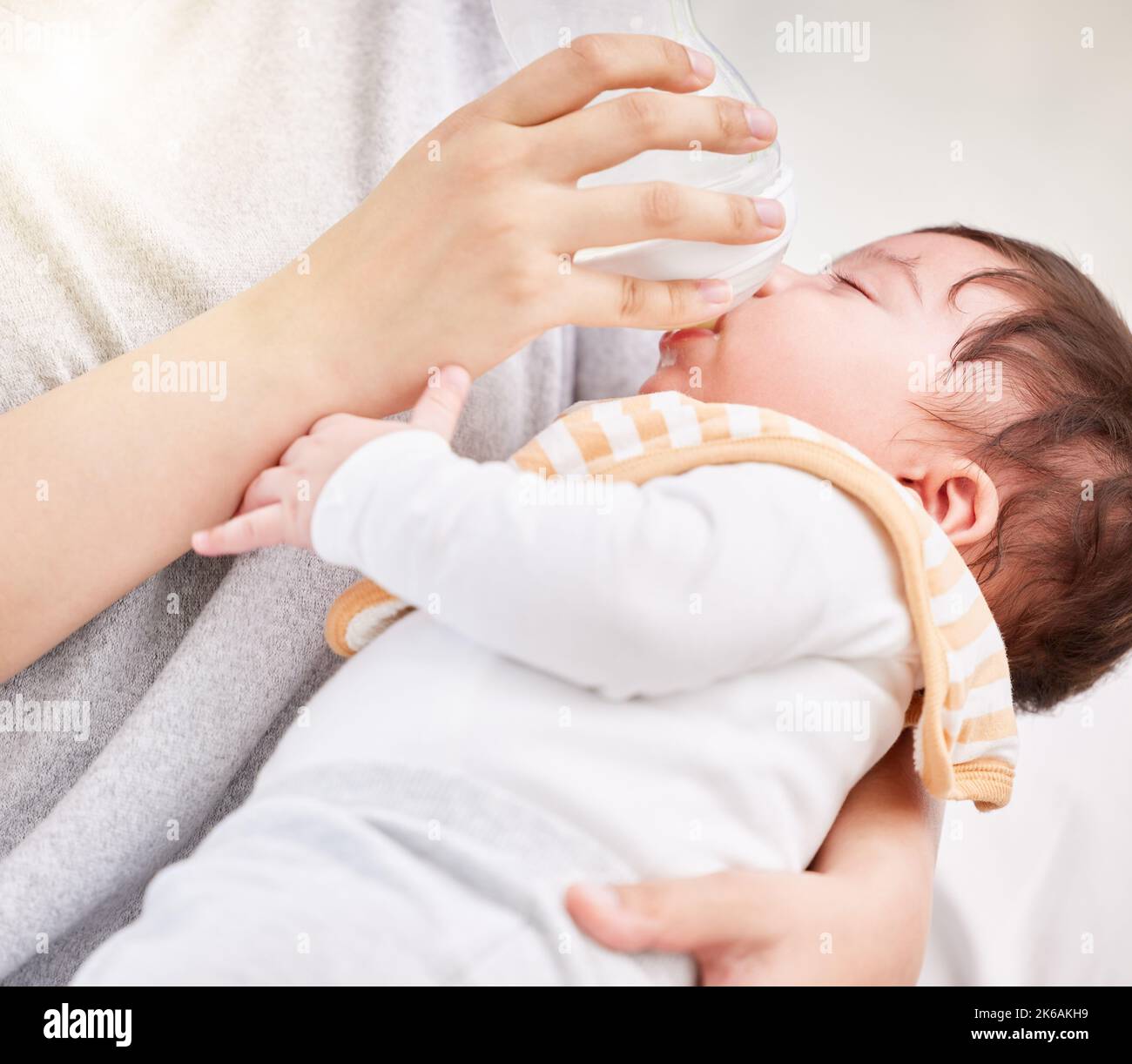 Closeup shot of a cute tired little newborn brunette mixed race baby being bottle fed by unknown single mother. Hispanic baby taking his routine nap Stock Photo