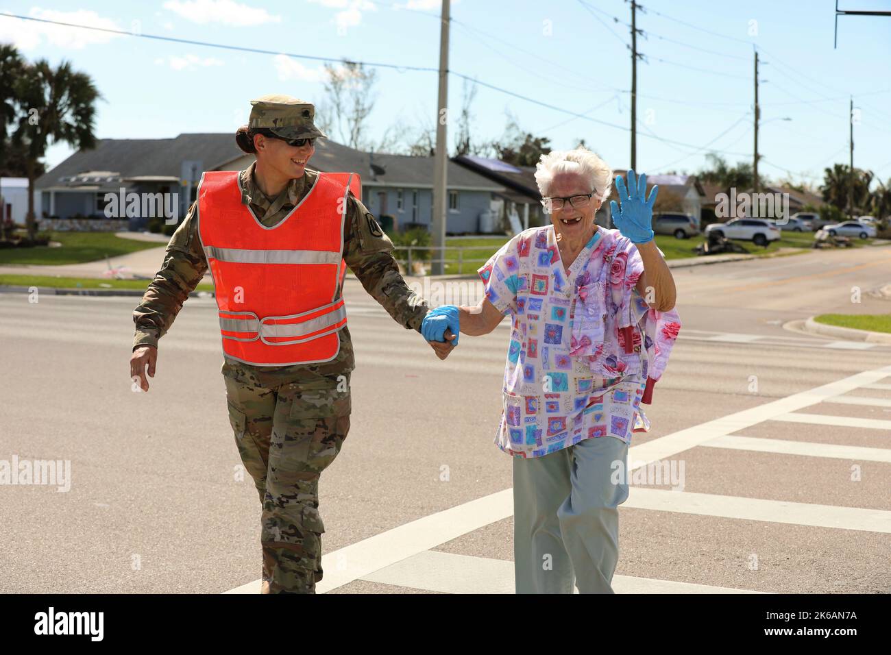 Port Charlotte, Florida, USA. 2nd Oct, 2022. Avenger Crew Member Spc. Elizabeth Strople, 1-256th Air Defense Artillery (ADA), aids Susan Williams cross a busy intersection while conducting traffic control for civilians and emergency responders in Port Charlotte, Fla.Over 6,000 service members were activated in response to the natural disaster along with both military and civilian support from out-of-state locations. Credit: U.S. Army/ZUMA Press Wire Service/ZUMAPRESS.com/Alamy Live News Stock Photo