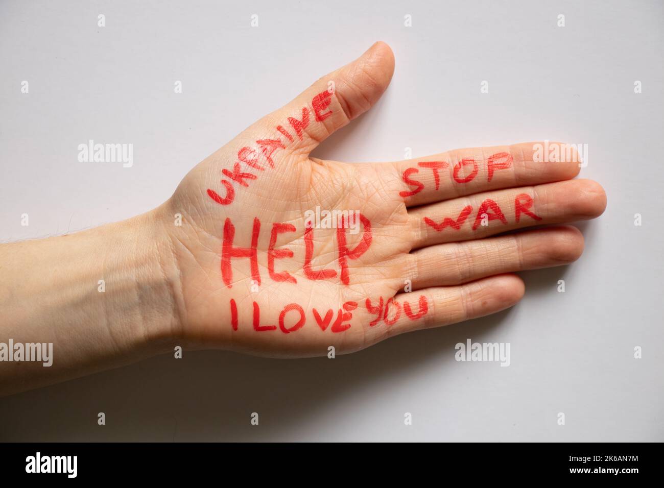Female hand with text help, stop war, I love you, Ukraine on isolated background, helping hand to peaceful Ukraine 2022 Stock Photo