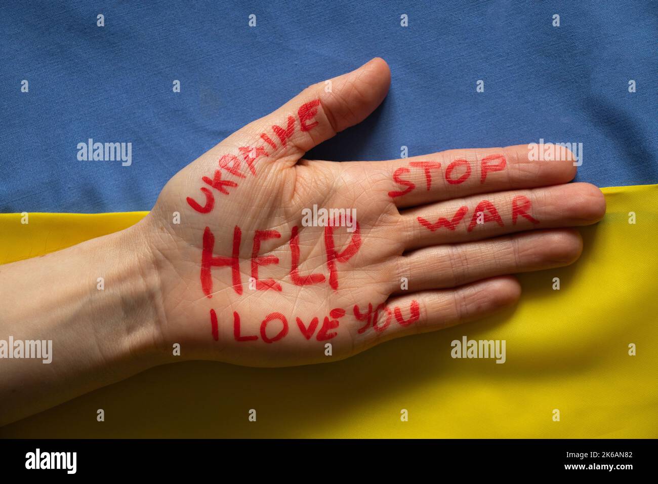 Female hand with text help, stop war, I love you, Ukraine on a white background, helping hand to peaceful Ukraine 2022 Stock Photo