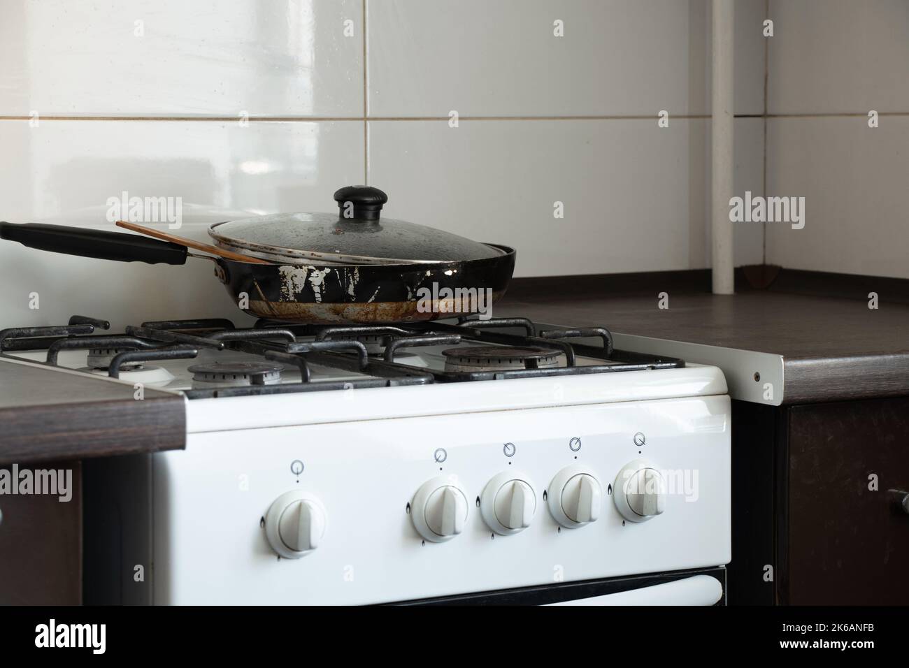 Gas stove and dirty frying pan in the kitchen in an apartment in Ukraine, kitchen furniture and appliances, kitchen interior Stock Photo