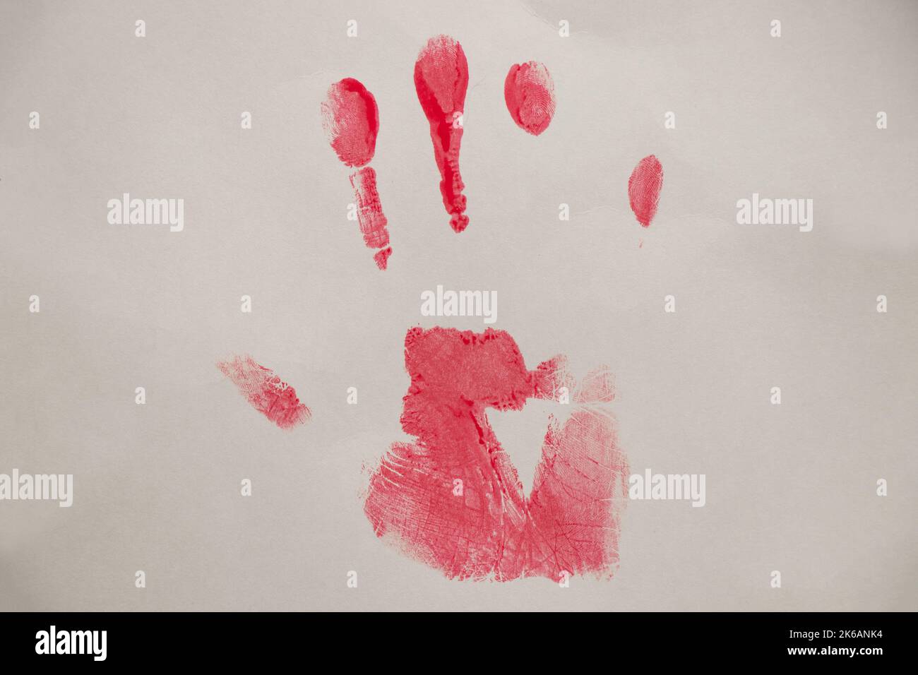 Trace of a hand from red paint on white paper close-up, a handprint on a white background Stock Photo