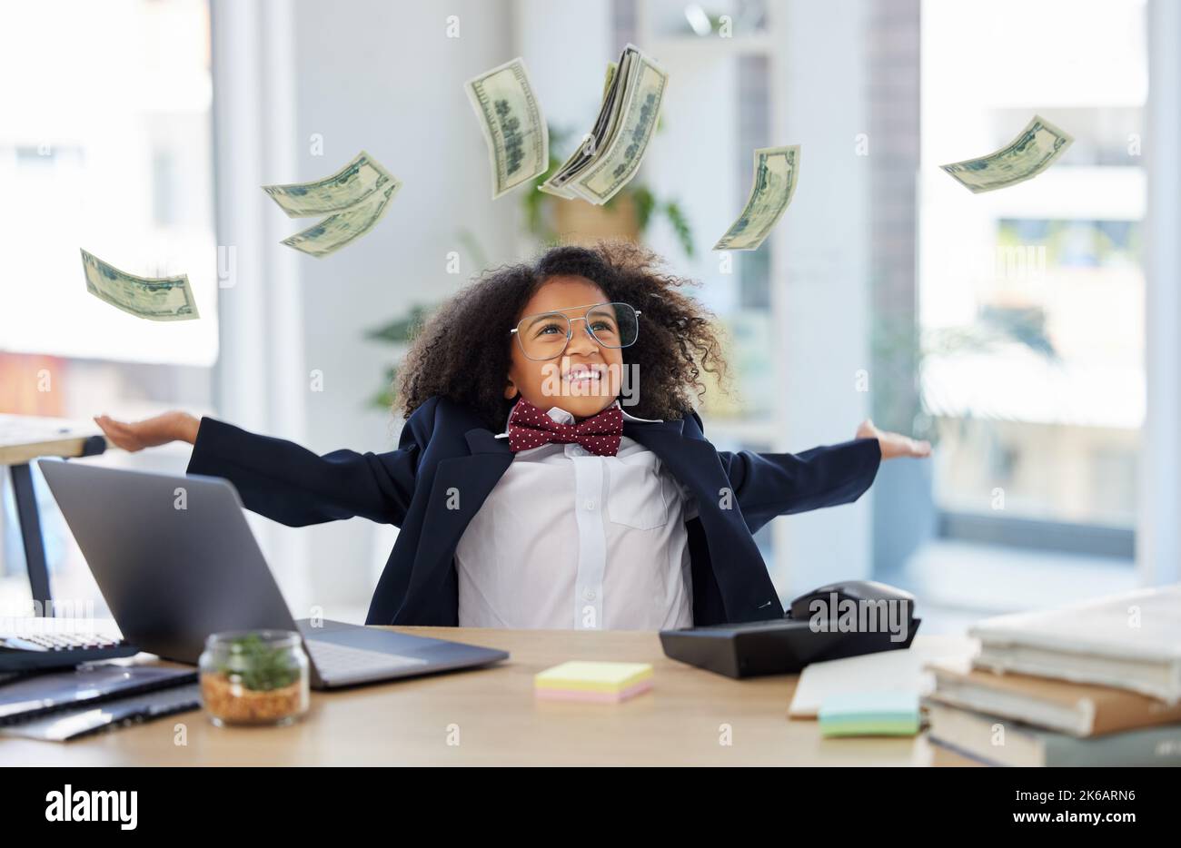 Money, money, money. an adorable little girl dressed as a businessperson sitting alone in an office and throwing money. Stock Photo