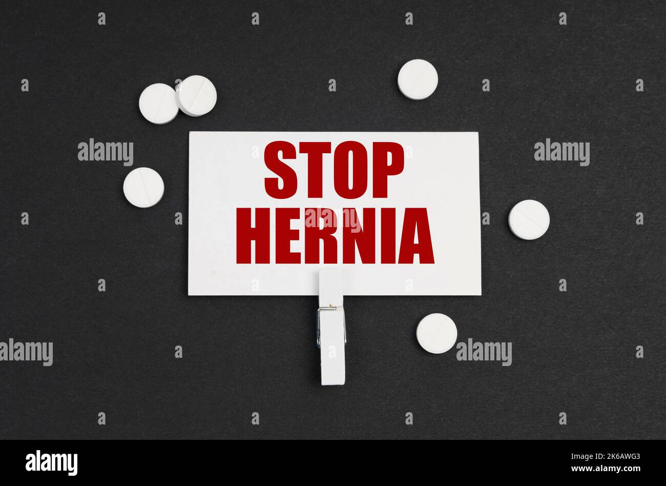 Medicine concept. On a black background, there are pills and a business card with the inscription - STOP HERNIA Stock Photo