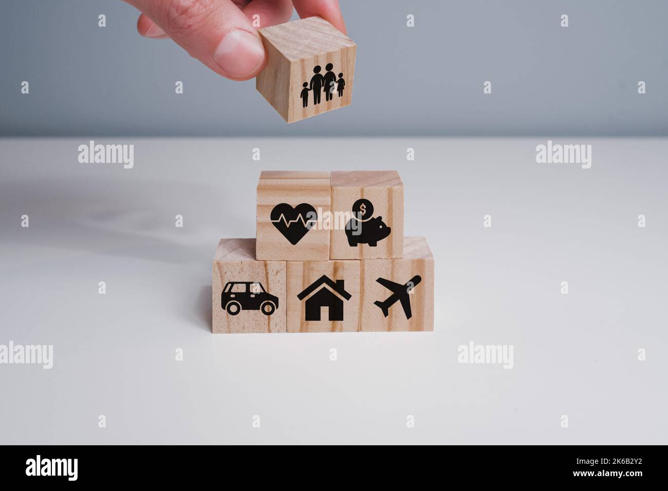 Hand of a man placing stacked wooden cube blocks with an icon of family ...
