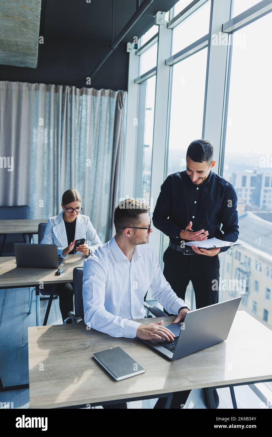 Modern office. Young team of businessmen in formal wear discussing ...
