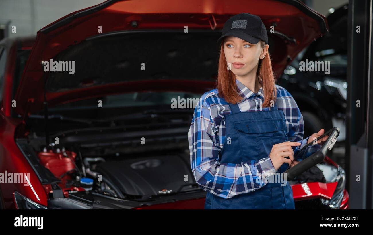 Caucasian female auto mechanic uses a special computer to diagnose