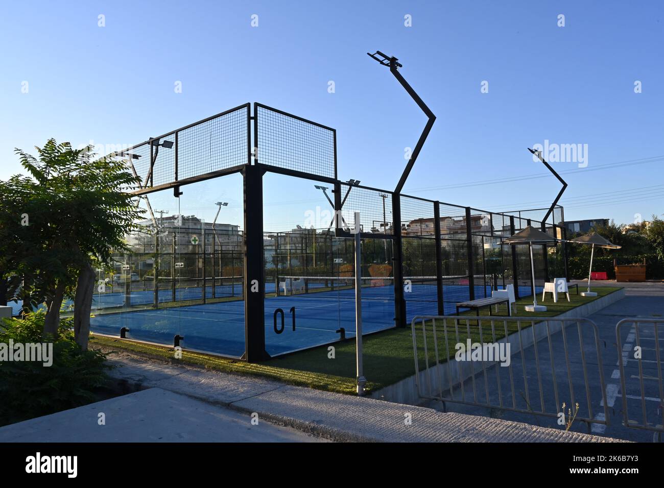 An enclosed blue court for padel with construction created by mesh and the glass back walls. Stock Photo