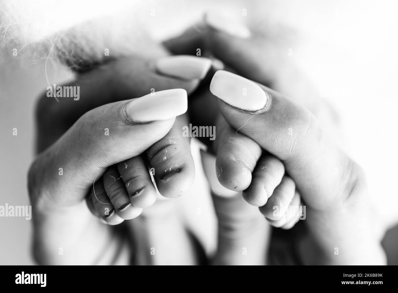 A mother hold a newborn baby by the legs. The feet of a newborn in the