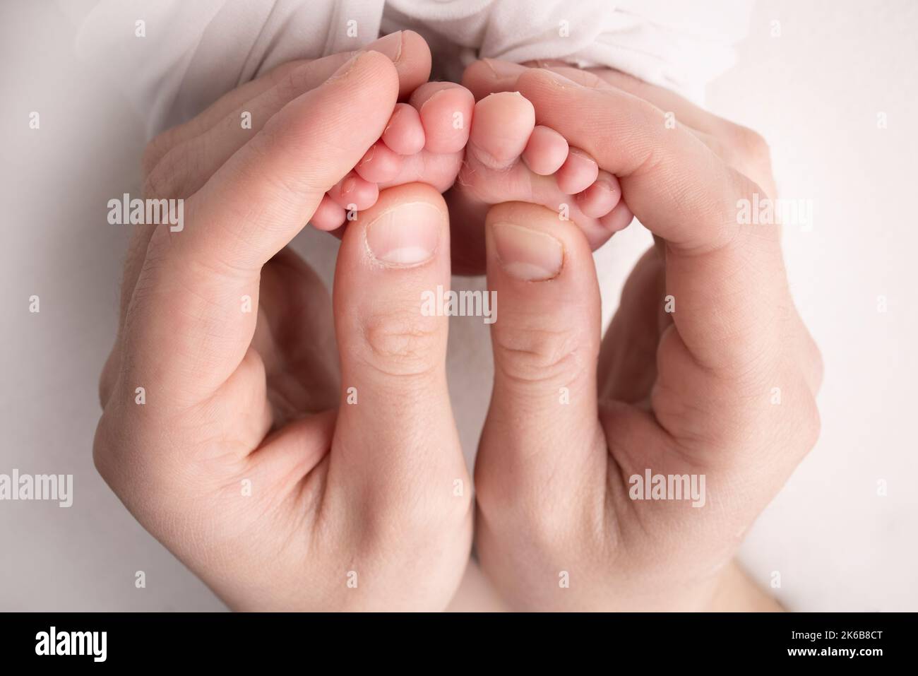 Mother is doing massage on her baby foot. Closeup baby feet in mother hands. Stock Photo