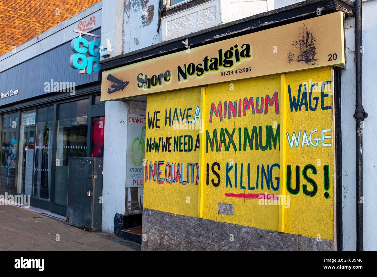 Empty shop front in the High Street with Minimum Wage slogan ShorehambySea , Sussex