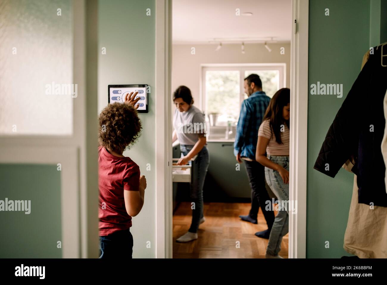 Boy using digital tablet while family in kitchen at home Stock Photo